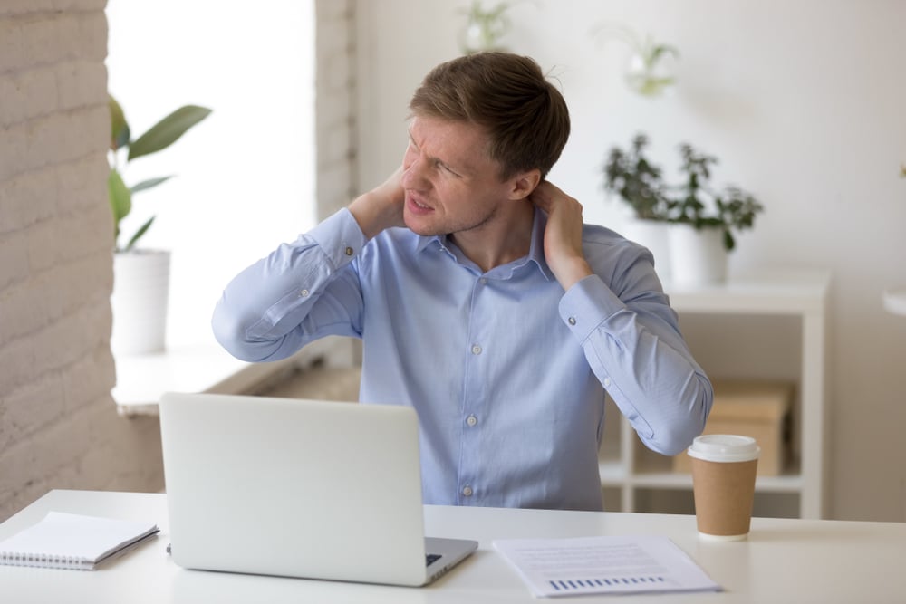 Man sitting at his computer feels pain in his neck. Man sitting at his computer feels pain in his neck.