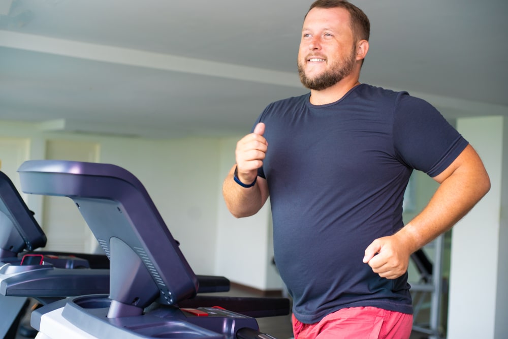 Man works out on treadmill to lose weight with doctor supervision. Man works out on treadmill to lose weight with doctor supervision.